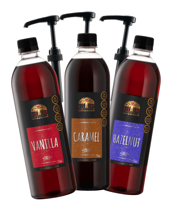 Three bottles of syrup with pump dispensers labeled Vanilla, Caramel, and Hazelnut on a black background.